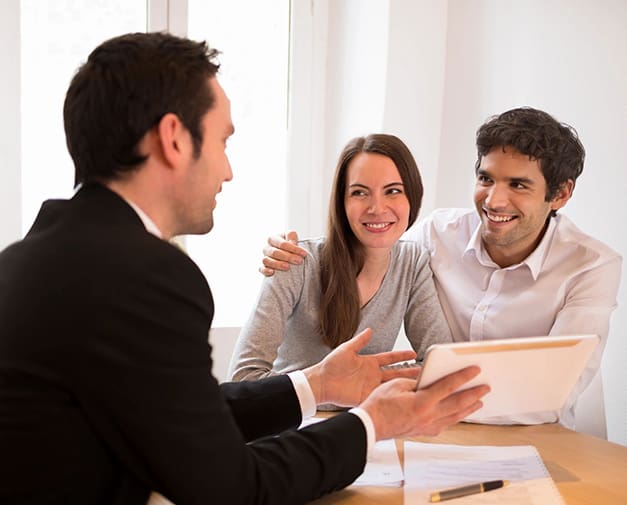 A man and two women sitting at a table with an ipad.