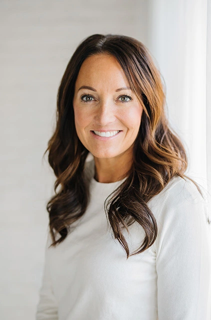 A woman with long brown hair wearing white shirt.