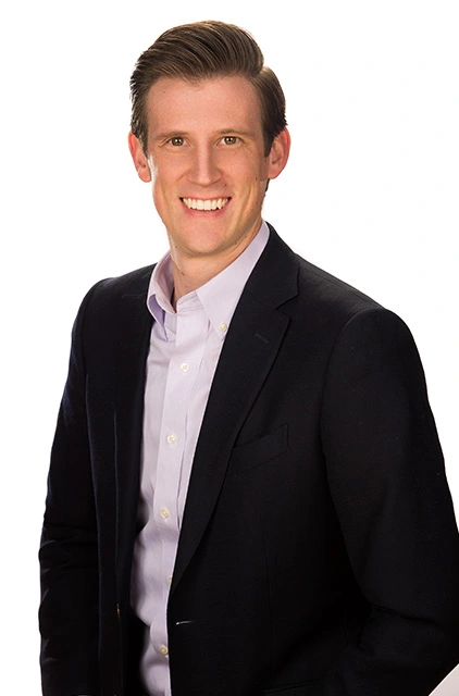 A man in a suit and shirt smiling for the camera.