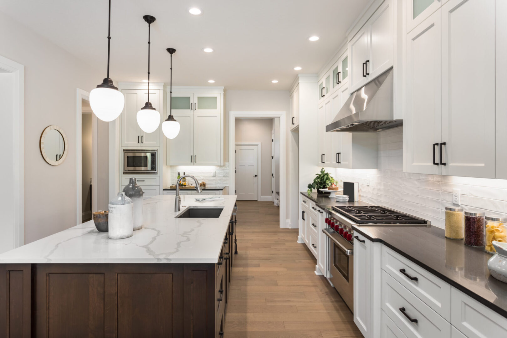 A kitchen with white cabinets and wooden floors.