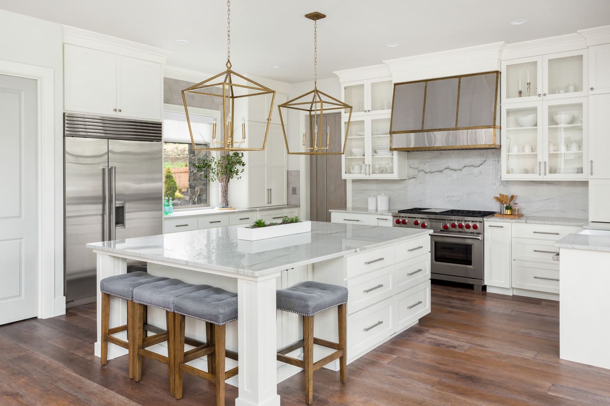 A kitchen with white cabinets and wooden floors.