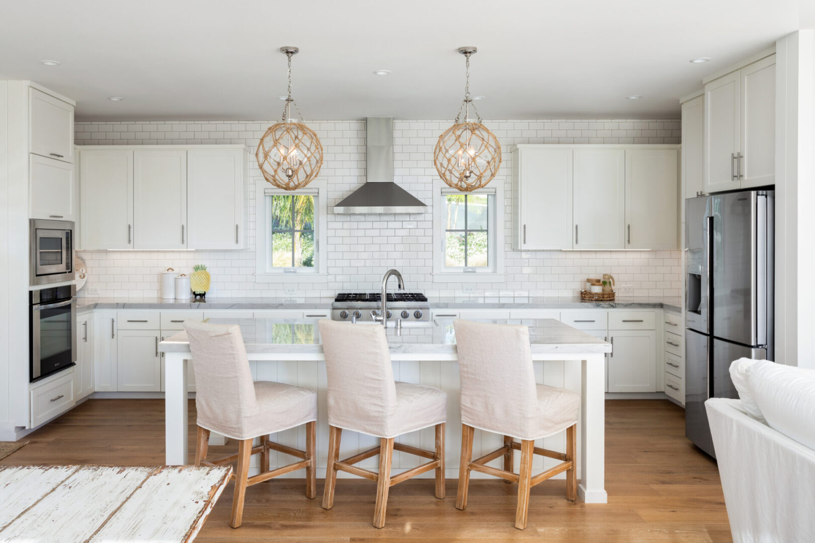 A kitchen with white cabinets and wooden floors.