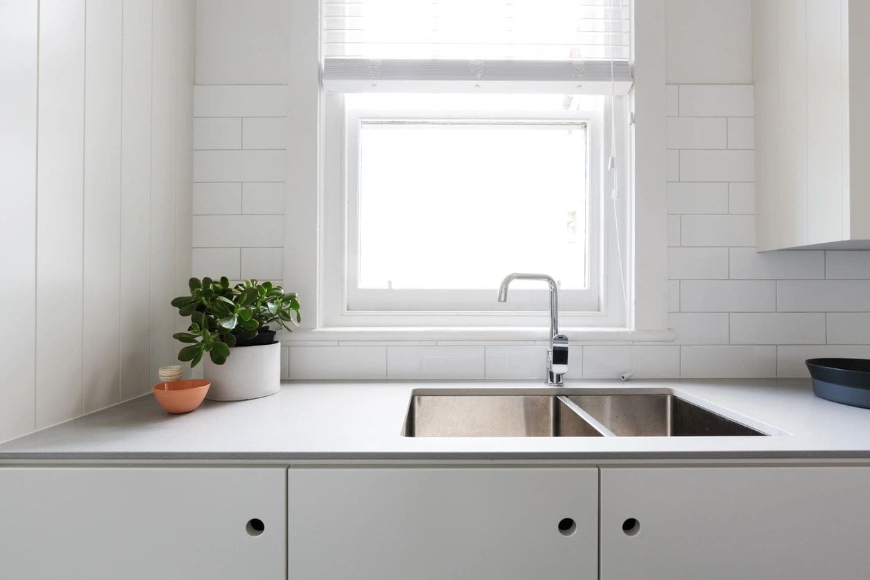 A kitchen with white walls and a sink.